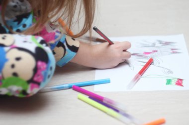 Bir kız çocukluk fantezilerini keçeli kalemlerle kağıda çizer..