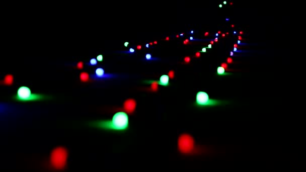 A garland blinking with colorful bright lights lying on the floor in the dark. — Stock Video