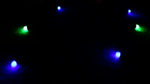 "Volando "sobre un centelleo multicolor luces brillantes una guirnalda que yace en el suelo en la oscuridad . — Vídeo de stock