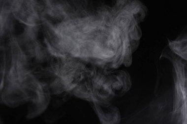 Siyah arka planda yayılan duman bulutları.