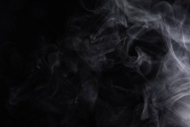 Siyah arka planda yayılan duman bulutları.