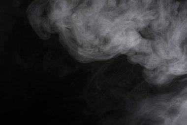 Siyah arka planda yayılan duman bulutları.