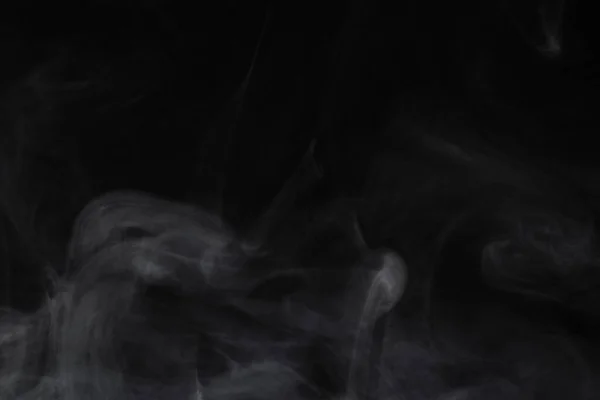 Puffs de fumaça espalhados em um fundo preto . — Fotografia de Stock