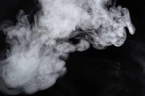 Puffar av rök sprids på en svart bakgrund. — Stockfoto