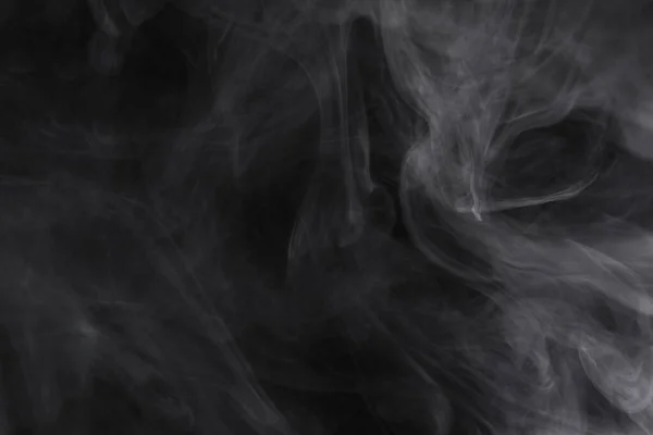 Obláčky kouře se šíří na černém pozadí. — Stock fotografie