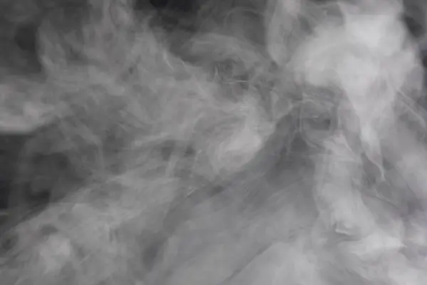 Духи дыма распространяются на черном фоне . — стоковое фото