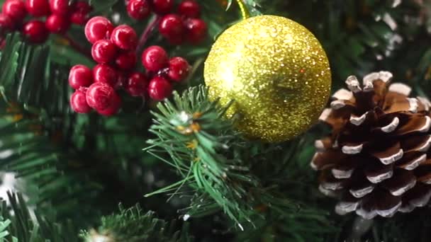 Feliz Navidad y un feliz año nuevo! Árbol de Navidad verde ligeramente espolvoreado con nieve. Árbol de plástico sobre un fondo claro con bayas artificiales y conos de pino natural "flota" delante de la lente . — Vídeo de stock