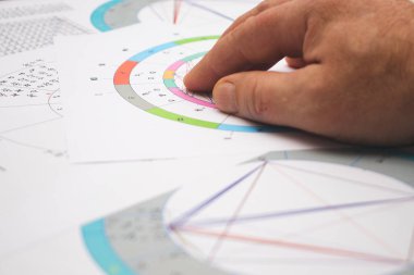 Modern bir astrologun işyeri. Bir astrologun aksesuarları. Bilgisayar astrolojik haritaları ve tabloların çıktıları. Astrolojik semboller ve işaretler.