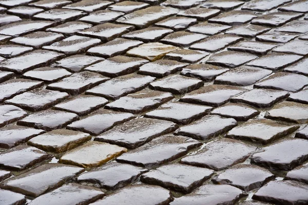 Mokrý povrch dlážděné ulice v dešti. — Stock fotografie