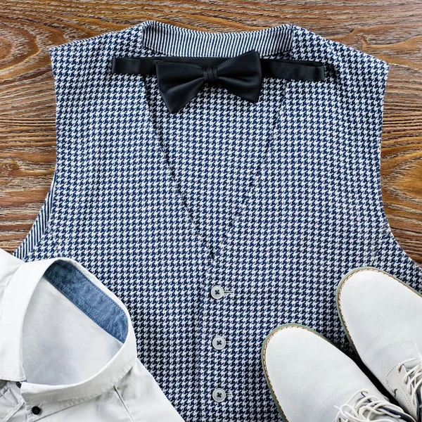 Mans classic clothes outfit flat lay with formal shirt, vest, bowtie, shoes.