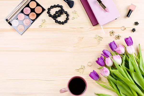 Flat lay with laptop, makeup items, tulip flowers, fashion accessories and stationery, modern woman office concept. Feminine accessories and work items on wooden table top, 8 March celebration