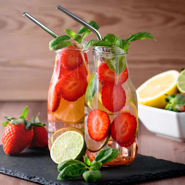 Refreshing drink or water with citrus fruits lemon and lime and basil in mason jar with reusable metal straws. Healthy lemonade drink in glass jar on kitchen table, zero waste, sustainable lifestyle