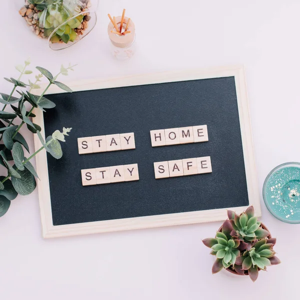 Words stay home, stay safe made of wooden blocks, concept of self quarantine at home as preventative measure against virus outbreak. Flat lay with inspiration quote, staying at home during emergency