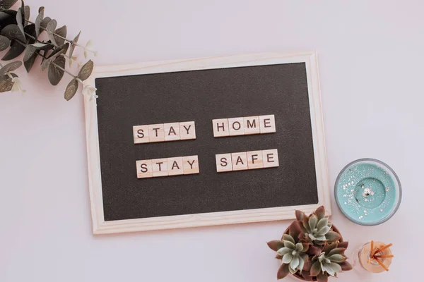Words stay home, stay safe made of wooden blocks, concept of self quarantine at home as preventative measure against virus outbreak. Flat lay with inspiration quote, staying at home during emergency
