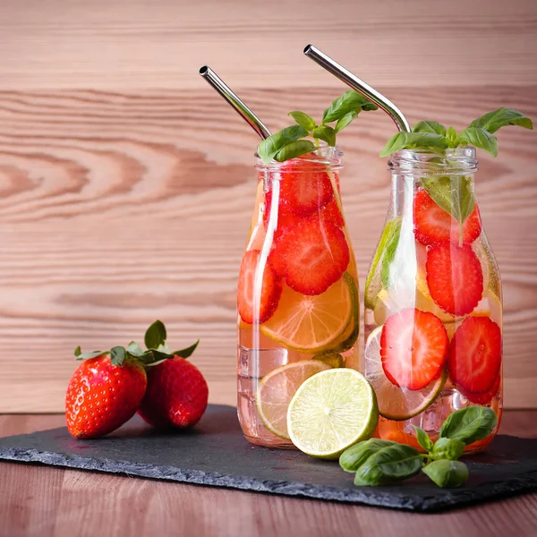 Refreshing drink or water with citrus fruits lemon and lime and basil in mason jar with reusable metal straws. Healthy lemonade drink in glass jar on kitchen table, zero waste, sustainable lifestyle