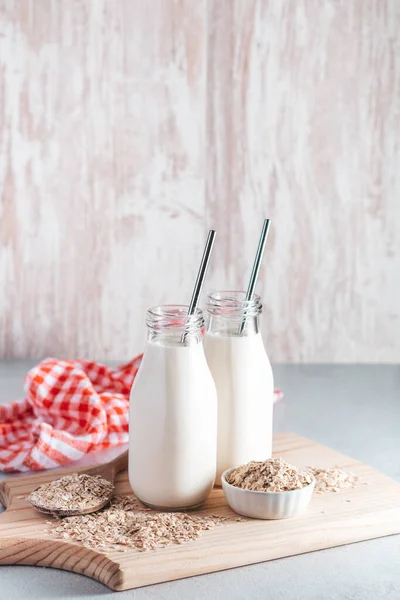 Non dairy oat milk in glass jars with reusable metal straws. Healthy vegan milk alternative still life, copy space. Substitute for traditional cow milk with oat flakes, healthy lifestyle concept