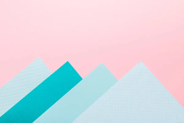 Paper geometric background in pink and mint green colors. Geometric shapes, minimalisctic backdrop with colored paper, frame, top view, copy space