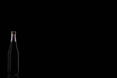 Siyah bir içecekle küçük bir cam şişe sol arka planda bir ayna yüzeyinde duruyor..