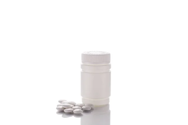 一个装有倒着药片的罐子站在镜子表面上 中间是白色的背景 — 图库照片