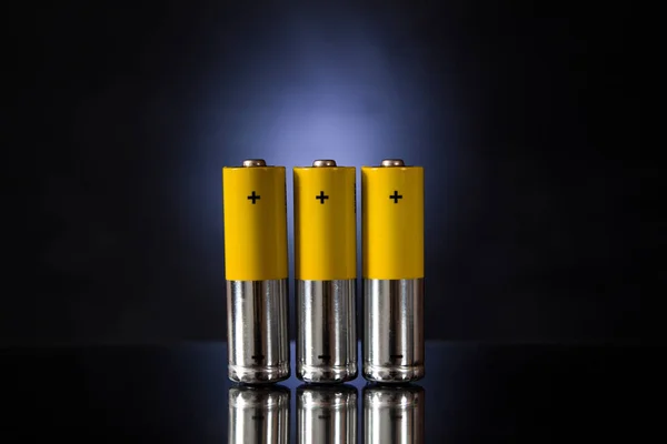 Three orange rechargeable batteries on a blue backlit background.