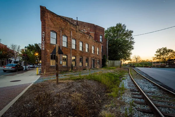 Järnvägsspåren och byggnader i solnedgången, i centrala Greensboro, — Stockfoto