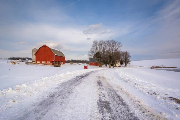 Snow covered road and red barn on a farm in a rural area of York — Stock Photo, Image