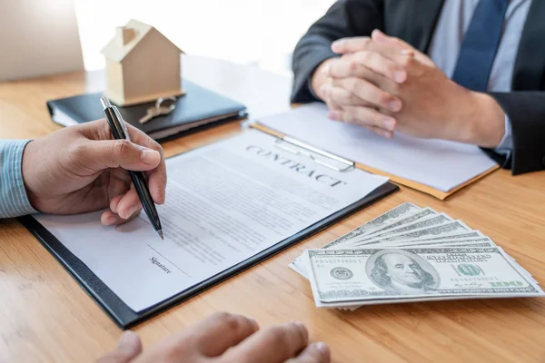 Businessman signs contract behind home architectural model Discu — Stock Photo, Image