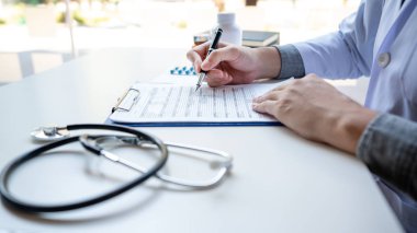 Doktor bir belge raporunu okuyor ve evrak işleriyle ilgili yazı yazıyor.