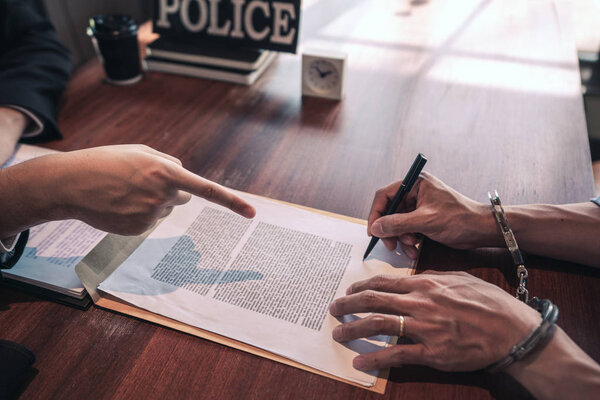 Офицер полиции допрашивает подозреваемого или преступника с гандку
