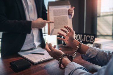 Police officer interrogating suspect or criminal man with handcu