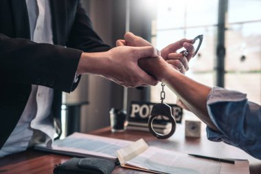 Police officer interrogating suspect or criminal man with handcu