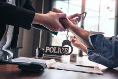 Police officer interrogating suspect or criminal man with handcu