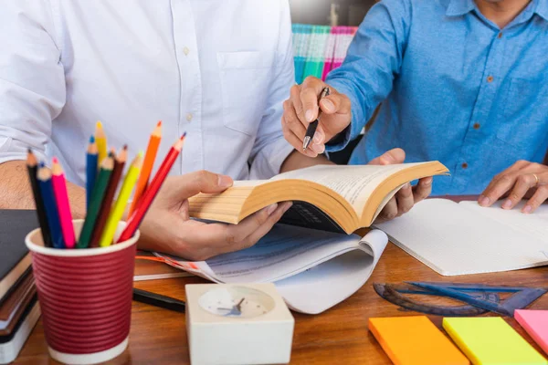 Tutor en universiteitsstudenten die schoolwerk geven en probleemoplossing uitleggen samen studeren en lezen in een tabel in de klas — Stockfoto