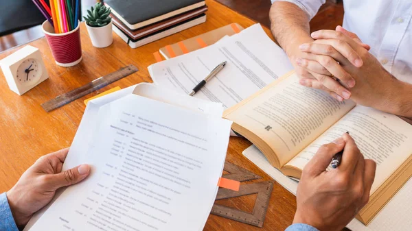 Tutor y estudiantes universitarios que enseñan trabajo escolar y explican la solución de problemas estudiando y leyendo juntos en una mesa en la sala de clases — Foto de Stock