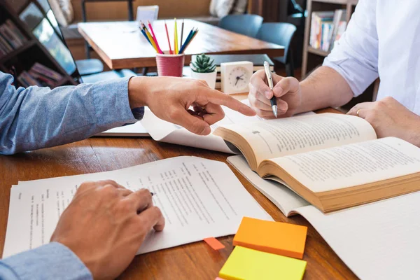 Tutor en universiteitsstudenten die schoolwerk geven en probleemoplossing uitleggen samen studeren en lezen in een tabel in de klas — Stockfoto