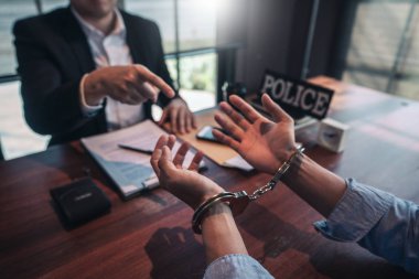 Police officer interrogating suspect or criminal man with handcu