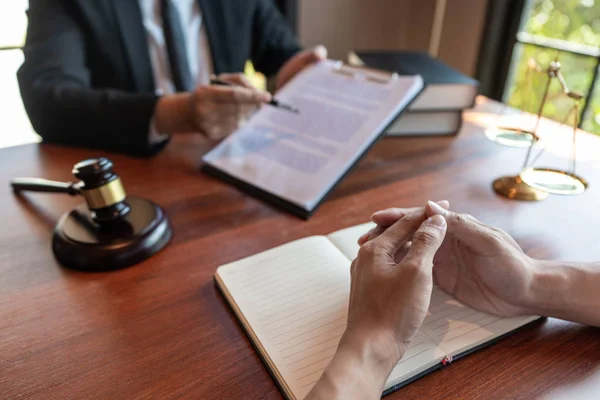 Адвокат, який працює з клієнтом, обговорює контрактні папери з латунними — стокове фото