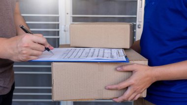 Paket alımını onayladıktan sonra müşteri kontrol listesi imzalaması için mavi üniformalı teslimatçı paket kutusu veriyor. 