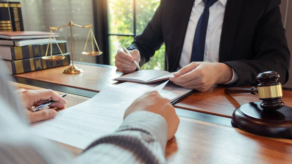 Lawyer working with client discussing contract papers with brass scale about legal legislation in courtroom, consulting to help their customer