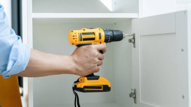 Beyaz erkek işçilerin portrelerini ve ellerinde elektrikli tornavida ile yeni ahşap masa ve ev geliştirme konseptini tamir ederken ki detaylarını kapat.