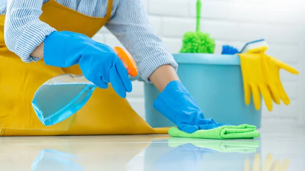 Housekeeper maid wearing rubber gloves with cloth cleaning or applying floor care and cleaners at home, housework and housekeeping concept