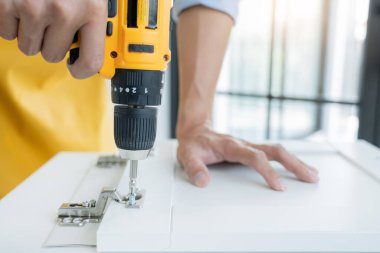 Beyaz erkek işçilerin portrelerini ve ellerinde elektrikli tornavida ile yeni ahşap masa ve ev geliştirme konseptini tamir ederken ki detaylarını kapat.