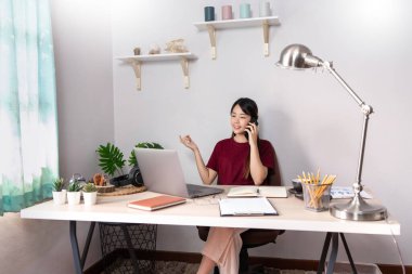 Düşünceli Asyalı kadın evde bilgisayarla uzaktan bilgisayarla çalışıp müşteriyle internet üzerinden iletişim kuruyor, E öğrenimi online sohbette öğretiyor, Coronavirus karantinası konsepti