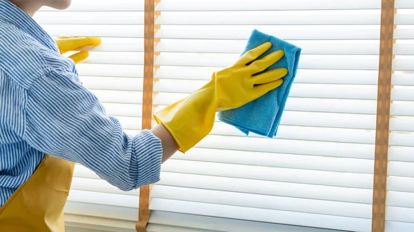 Young female spring cleaning house interior holding a duster for wiping dust dusting furniture at home