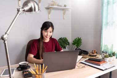 Düşünceli Asyalı kadın evde bilgisayarla uzaktan bilgisayarla çalışıp müşteriyle internet üzerinden iletişim kuruyor, E öğrenimi online sohbette öğretiyor, Coronavirus karantinası konsepti