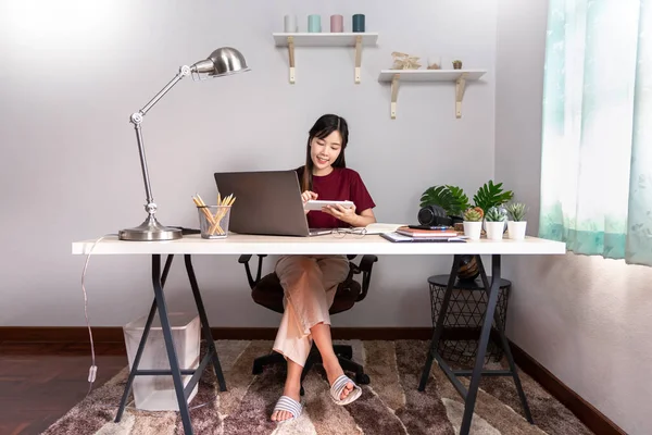 Pensive asian woman is relaxing on  desktop working remotely from home with laptop for communicates on internet with customer, E learning learn teach in online chat, quarantine Coronavirus concept