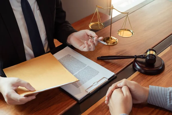 依頼人と仕事をする弁護士は 法廷での法規制に関する真鍮のスケールで契約書を議論し 顧客を助けるためにコンサルティング — ストック写真