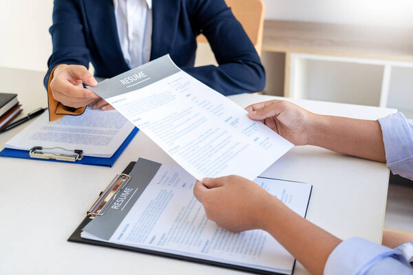 Интервью о работе и найме, женщины-кандидатки на собеседовании объясняя о своем профиле бизнес-менеджеру в современном офисном пространстве. Консультации или трудоустройство