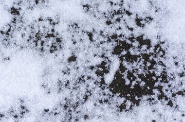 Garaj yolunda eriyen karlı gri asfalt dokusu. Bahar ve kış mevsiminin soyut kaba yüzeyi kavramı. Yoldaki yağış miktarına yakın çekim. Kopyalama alanı olan minimalist tasarım