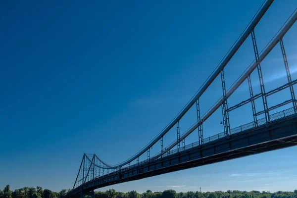 Vista da longa ponte bonita a partir do lado abaixo. Um caminho para o outro lado com árvores contra um céu azul sem nuvens em um dia claro. Conceito minimalista de juntar-se a um lugar para o texto . — Fotografia de Stock